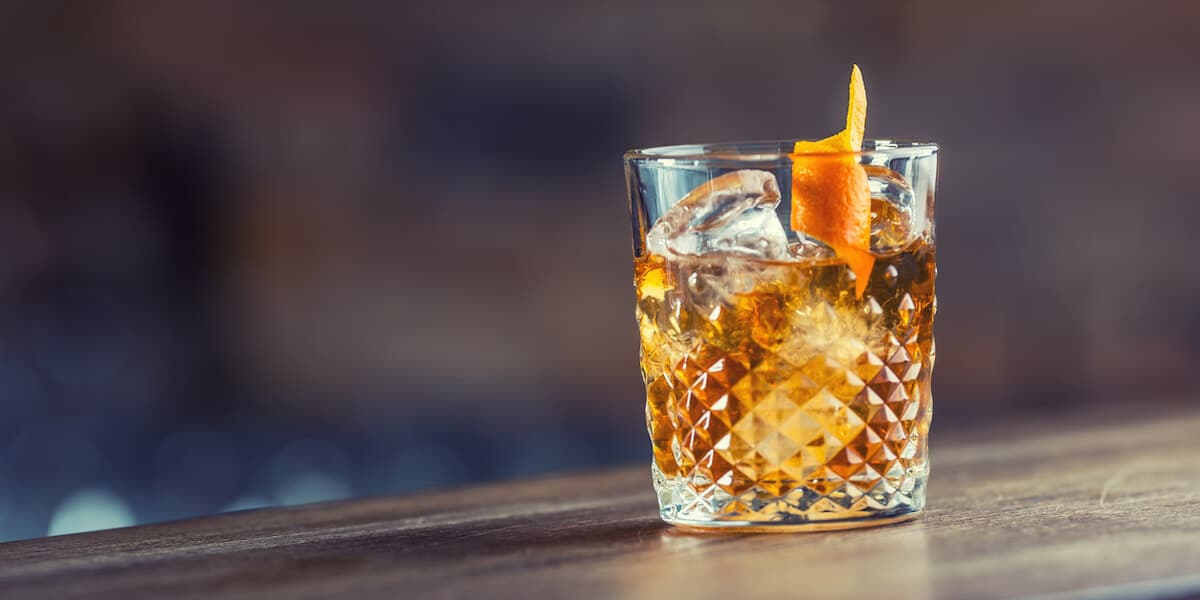 Old fashioned classic cocktail drink in crystal glass on bar counter